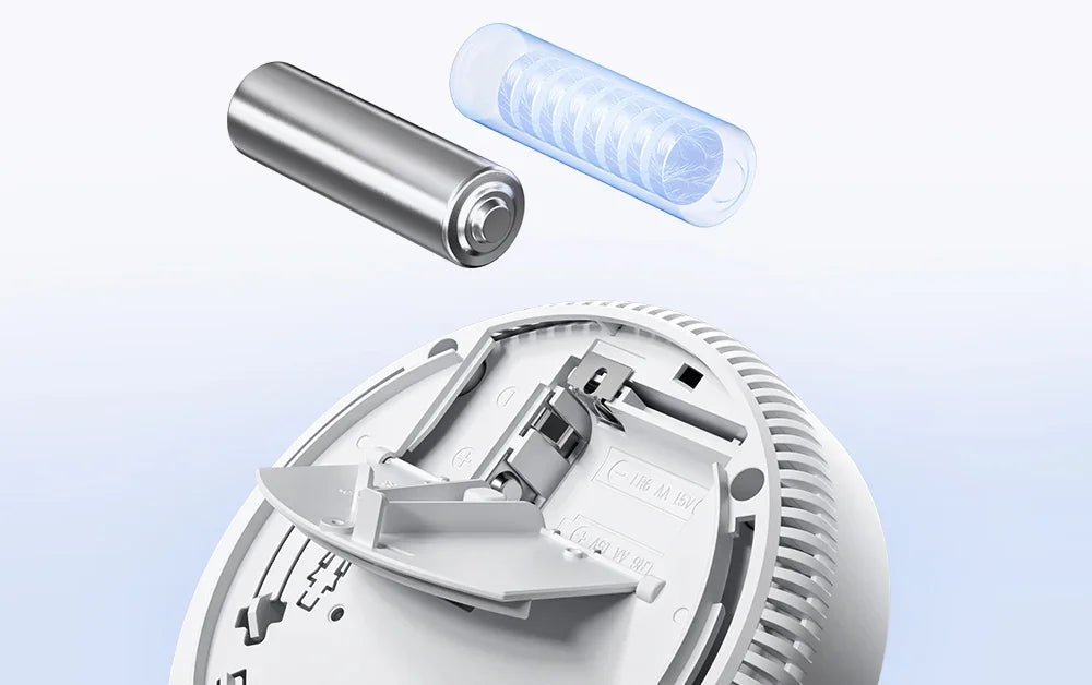Battery being fitted into the open battery compartment of a smoke alarm
